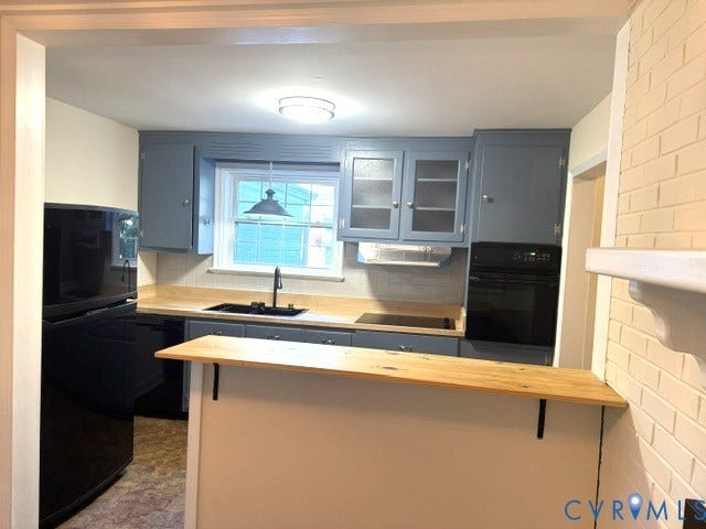 Kitchen featuring grey cabinetry, light wood-finish countertops, and a black sink with a matte black faucet