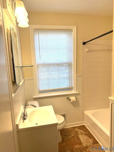 White vanity with an integrated sink, chrome faucet, and beadboard wainscoting
