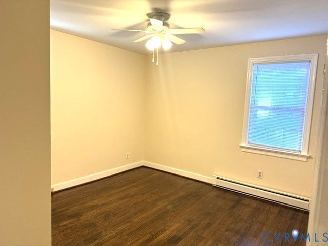 Rich wood-finish flooring, ceiling fan with integrated lighting, and a window with blinds provide comfort
