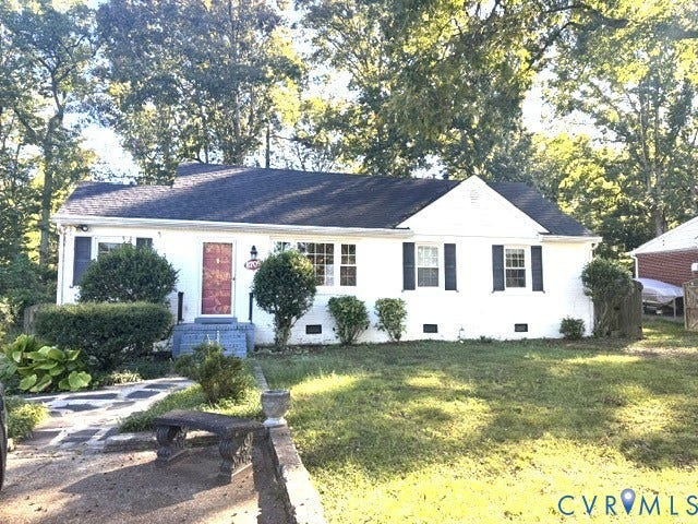 Classic cottage-style home featuring a crisp white exterior with dark shutters, a welcoming red entry door, and a dark pitched roof