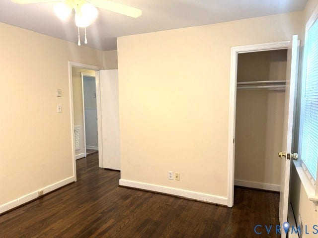 Rich wood-finish flooring, neutral wall tones, and overhead ceiling fan