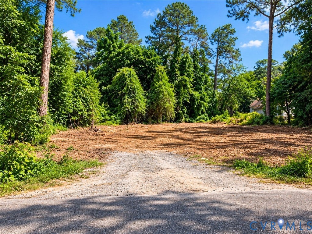 Cleared lot with a gravel entry, surrounded by mature trees