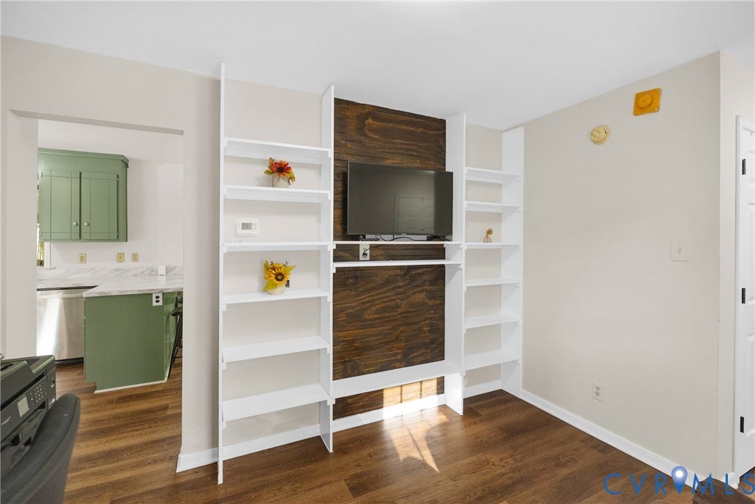 11512 Wiltstaff Drive, Midlothian, VA 23112 Built-in white shelving flanking a dark wood-finish accent wall with integrated television mount and wood-finish flooring