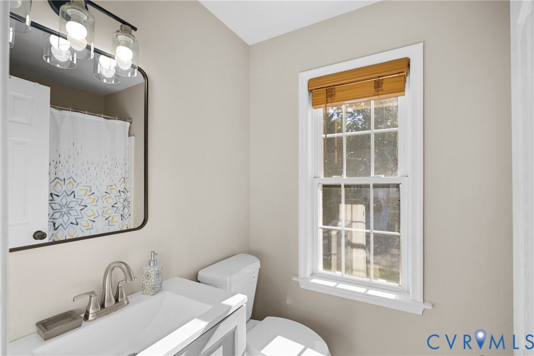 11512 Wiltstaff Drive, Midlothian, VA 23112 Bathroom featuring a vanity with a white rectangular sink, brushed nickel faucet, wall-mounted mirror with rounded corners, three-light vanity fixture, and a multi-pane window
