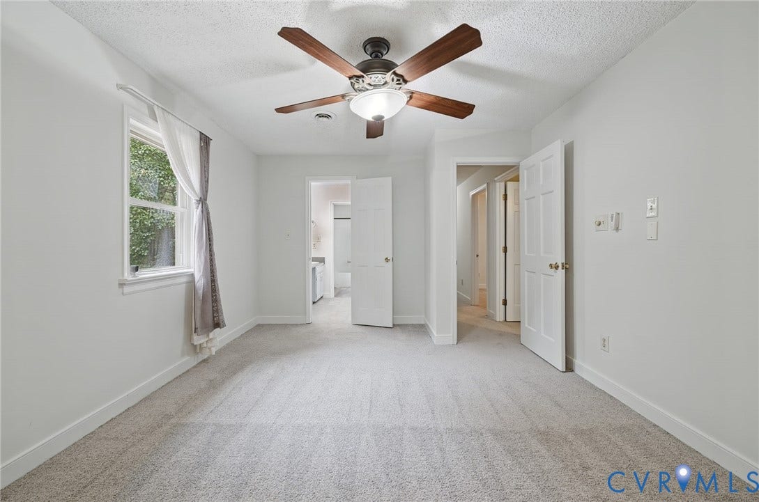 Interior room featuring neutral wall-to-wall carpeting, a multi-blade ceiling fan with integrated lighting, and a window with a single pane