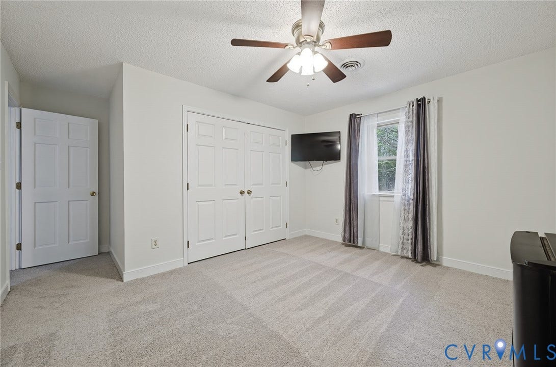 Neutral-toned wall-to-wall carpeting, ceiling fan with integrated lighting, and dual-panel closet doors