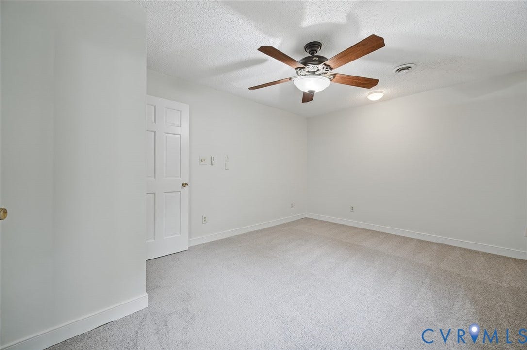 Interior room featuring wall-to-wall carpeting, a six-panel door, and a ceiling fan with integrated lighting