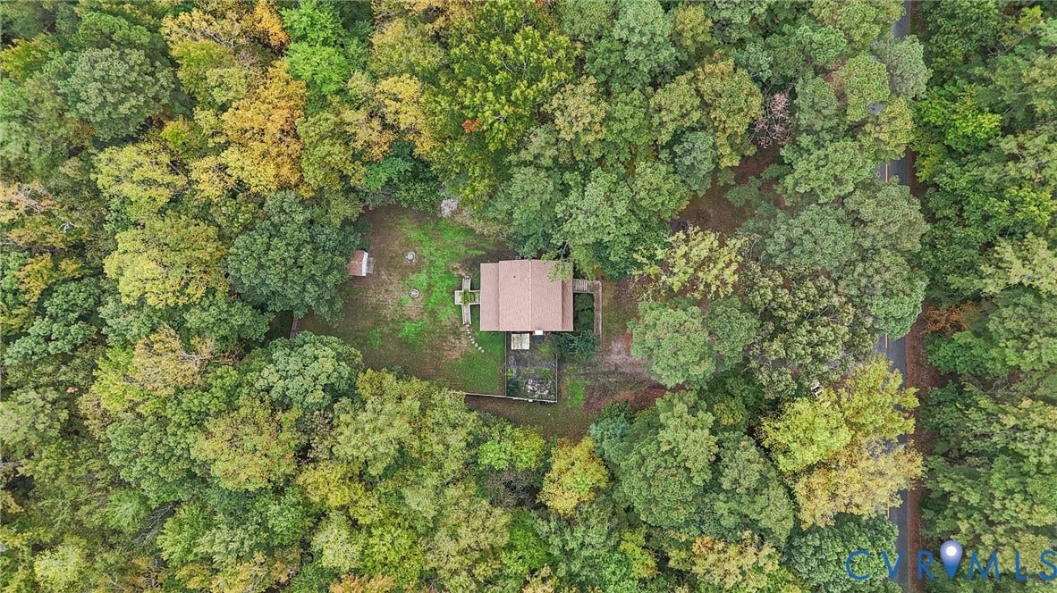 Aerial perspective of a detached residence situated on a secluded lot surrounded by mature deciduous and coniferous trees