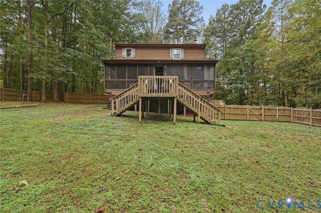 Two-story exterior featuring wood siding, a screened-in porch, an elevated wood deck with stairs, and a fenced perimeter