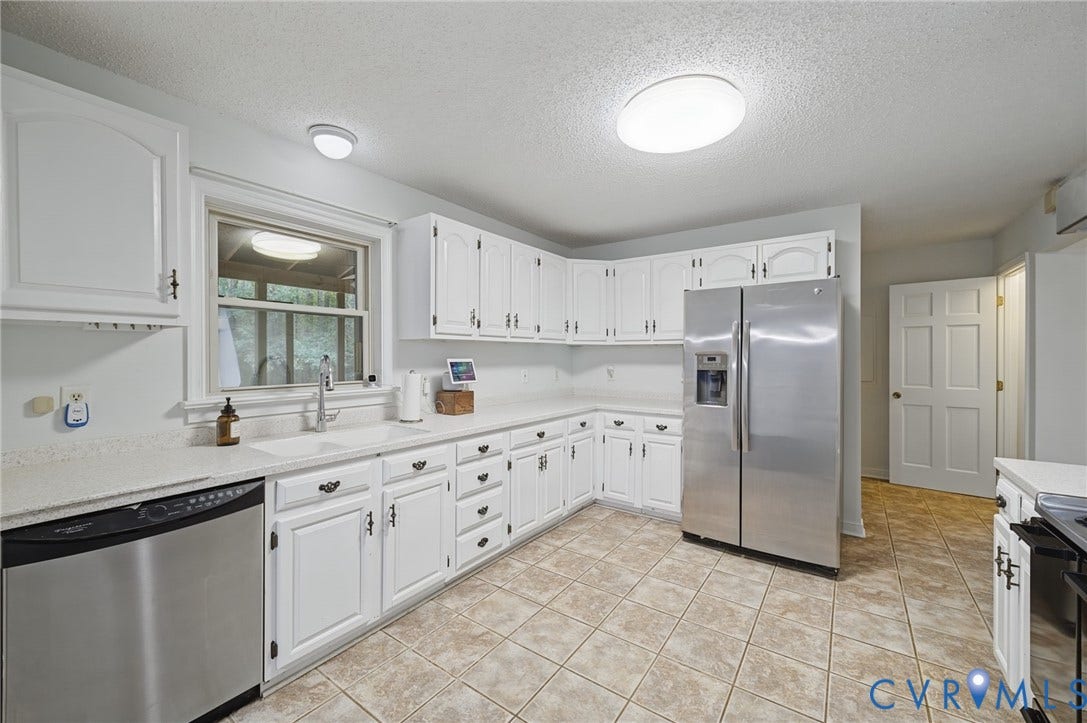 Kitchen featuring white shaker-style cabinetry, solid-surface countertops, stainless steel appliances, and ceramic tile flooring