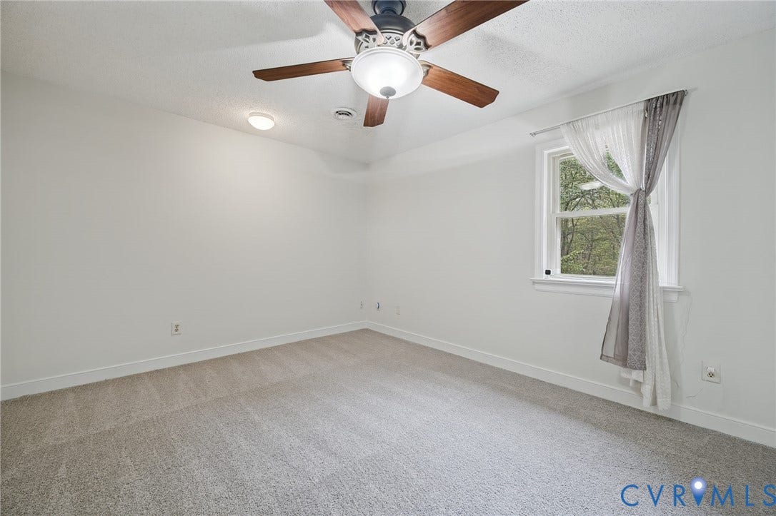 Neutral wall finishes, neutral carpeting, flush-mount lighting, and a multi-blade ceiling fan with an integrated light fixture