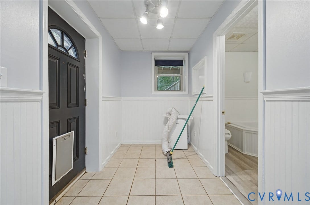 Entryway featuring wainscoting, ceramic tile flooring, and a multi-pane door with an integrated pet portal