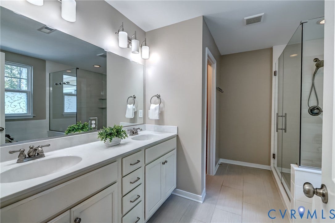 14800 Diamond Creek Terrace, Midlothian, VA 23113 Dual vanity with ample counter space, a glass-enclosed shower, white cabinetry, and subtle, multi-tonal vertically stripped tile.