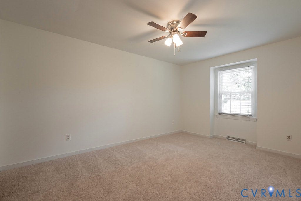 Neutral carpet flooring, white painted walls, single window with blinds, and a ceiling fan with integrated lighting