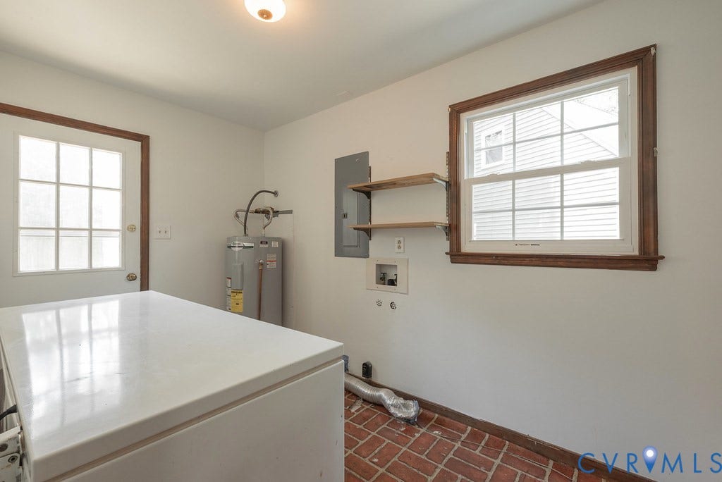 Brick flooring, white paneled door with window, single-pane window with wood trim, wall-mounted shelving