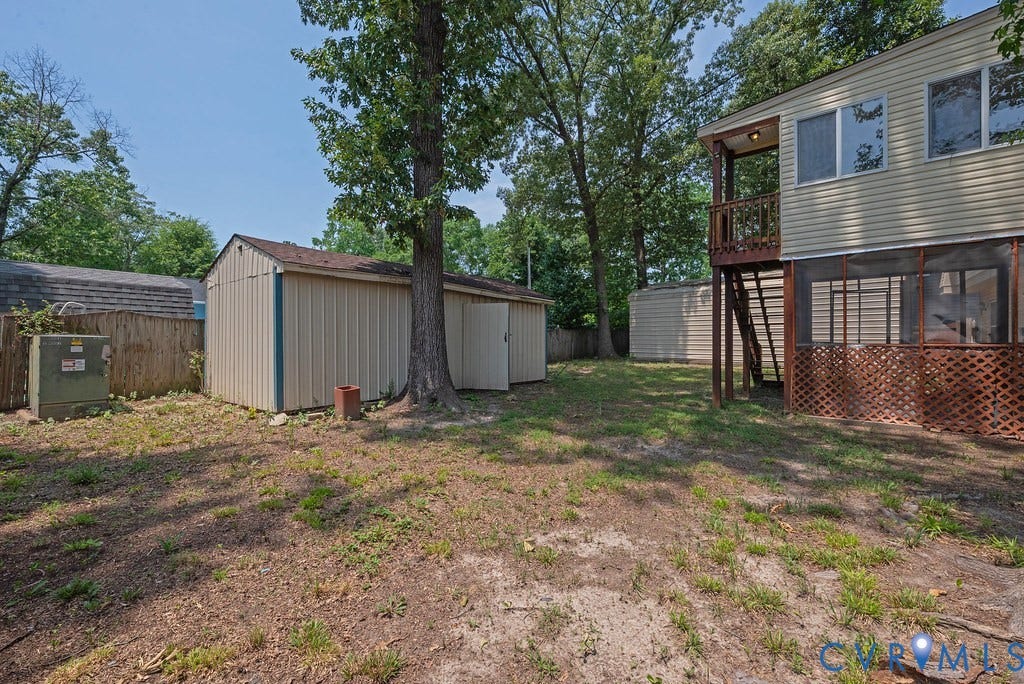 Rear exterior featuring a screened-in porch with lattice trim, an upper-level balcony, and two detached storage sheds