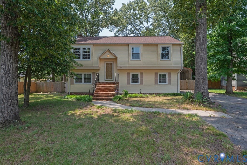 Two-story residence with light yellow siding, a prominent brick staircase, and a covered entry