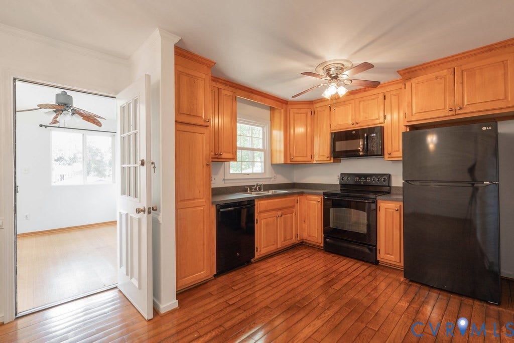 Kitchen featuring wood-finish flooring, wood cabinetry, dark countertops, and black appliances