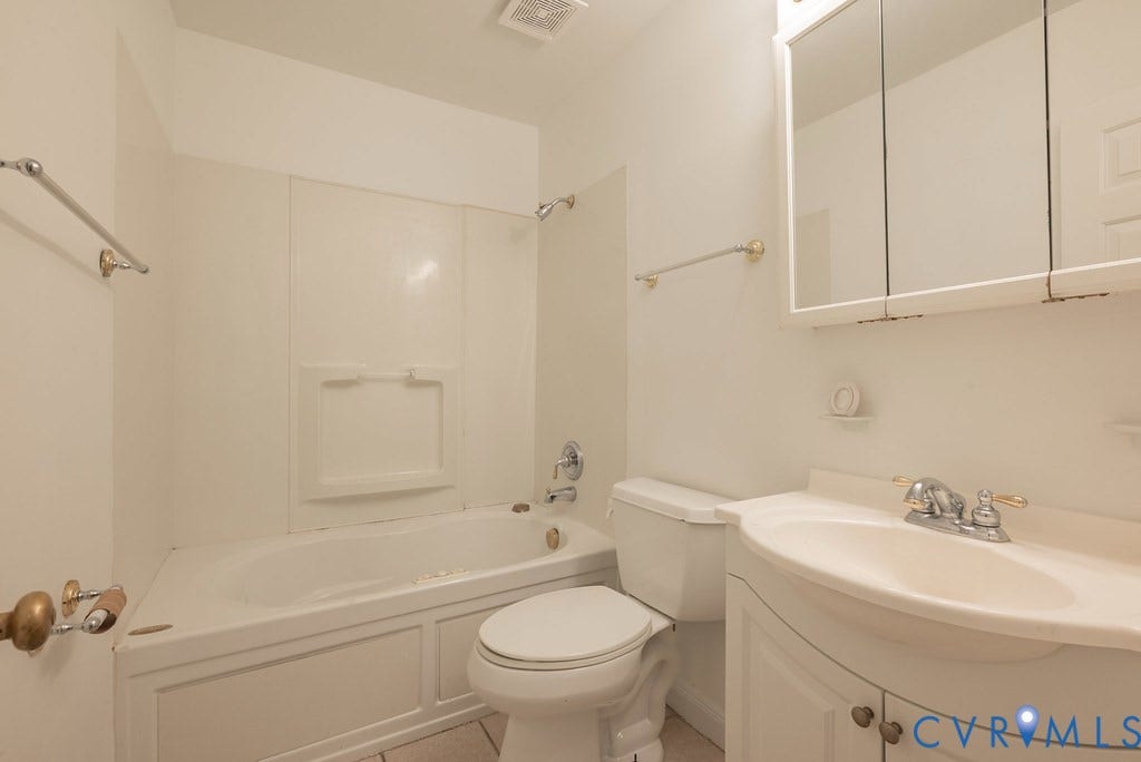 White bathroom vanity with curved front and integrated sink, chrome faucet, wall-mounted medicine cabinet with mirrored doors, white toilet, and white bathtub with shower