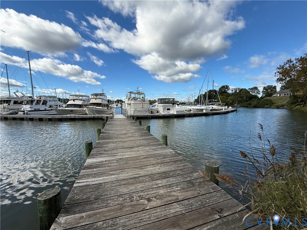 #30 Molly's Way, Urbanna, VA 23175 Wood-plank dock extending over water, surrounded by boats and a treeline