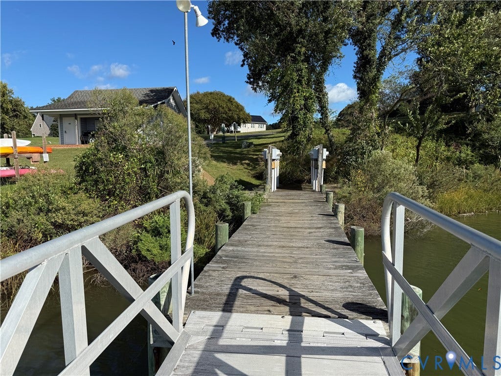 #30 Molly's Way, Urbanna, VA 23175 Wooden dock with metal railings, surrounded by lush vegetation and a visible body of water