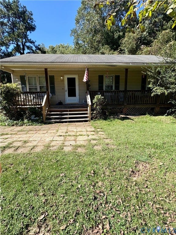 Front exterior with light-colored siding, a covered porch, and a paved walkway