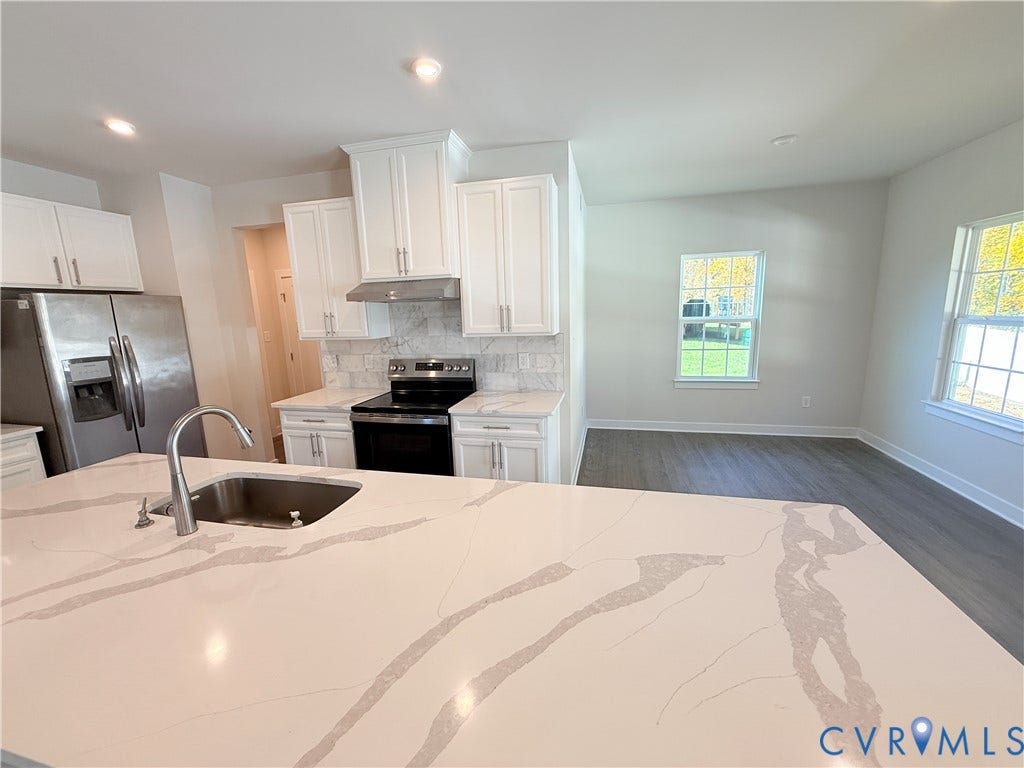 14225 Botsford Avenue, Wellspring, Chester, VA 23831 Kitchen featuring white shaker-style cabinetry, a quartz countertop island with an undermount sink, stone-finish backsplash, stainless steel appliances, and wood-finish flooring