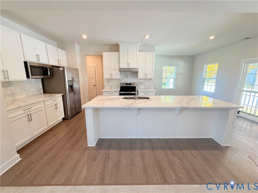 14225 Botsford Avenue, Wellspring, Chester, VA 23831 Kitchen featuring a large central island with a quartz countertop, white Shaker-style cabinetry, stainless steel appliances, tile backsplash, and wood-finish flooring