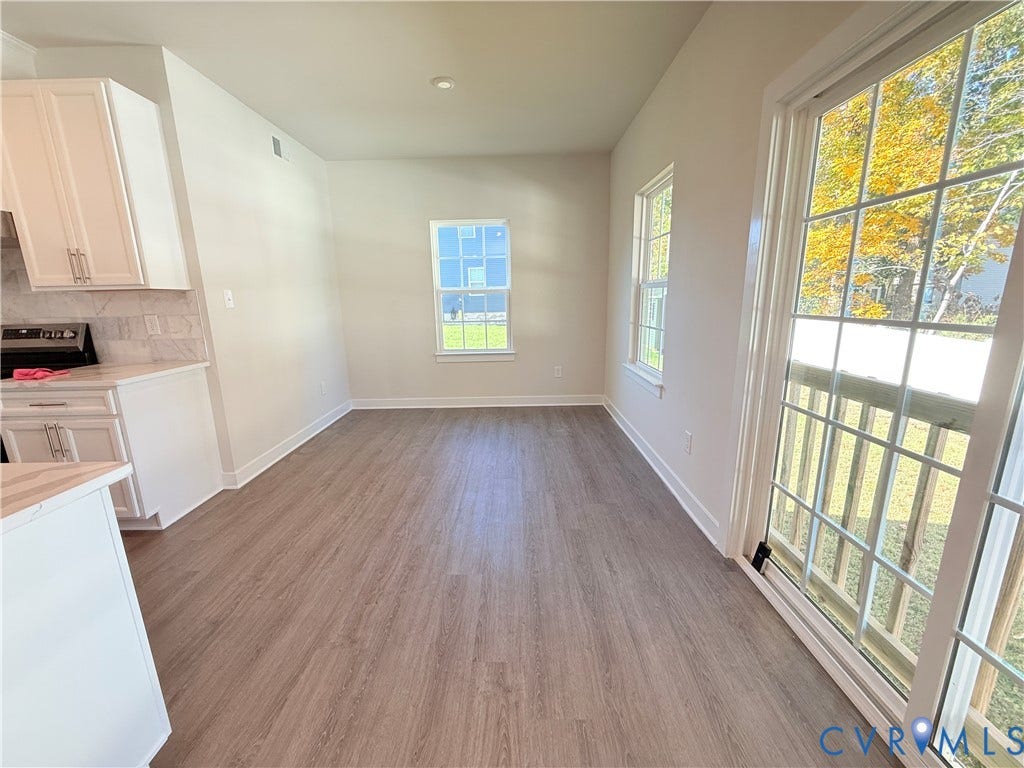 14225 Botsford Avenue, Wellspring, Chester, VA 23831 Wood-finish flooring, white cabinetry, quartz countertops, tile backsplash, and sliding glass door with muntin detailing