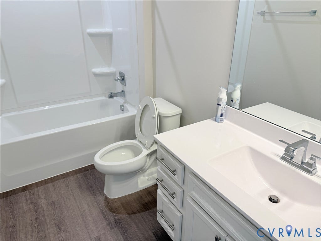 14225 Botsford Avenue, Wellspring, Chester, VA 23831 Bathroom featuring a white vanity with a composite countertop and integrated basin, wood-finish flooring, and a tub-shower combination with a surround