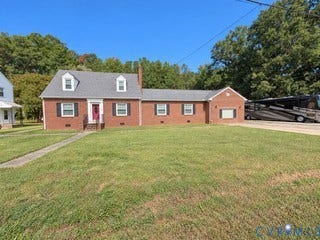 Brick exterior with a dormer roof, concrete walkway, and a paved driveway