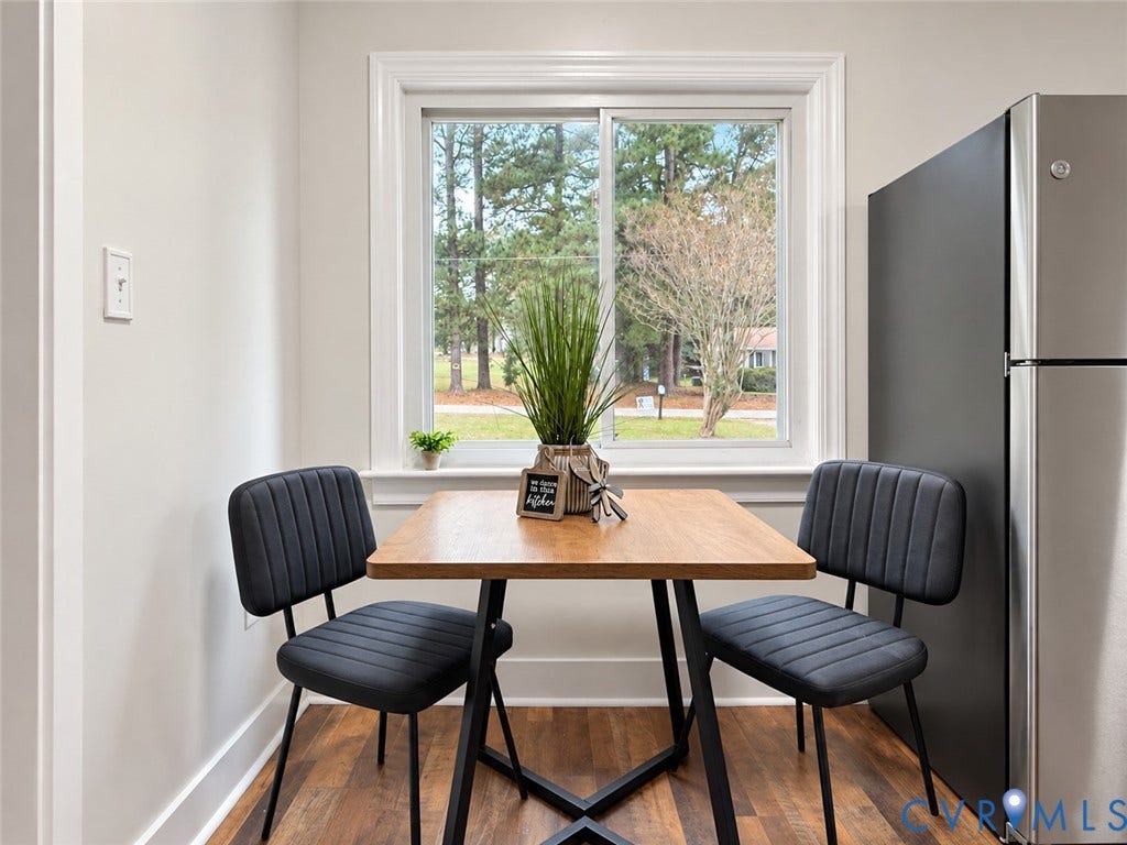 Wood-finish flooring with a neutral wall color, white window trim, and a built-in stainless steel refrigerator