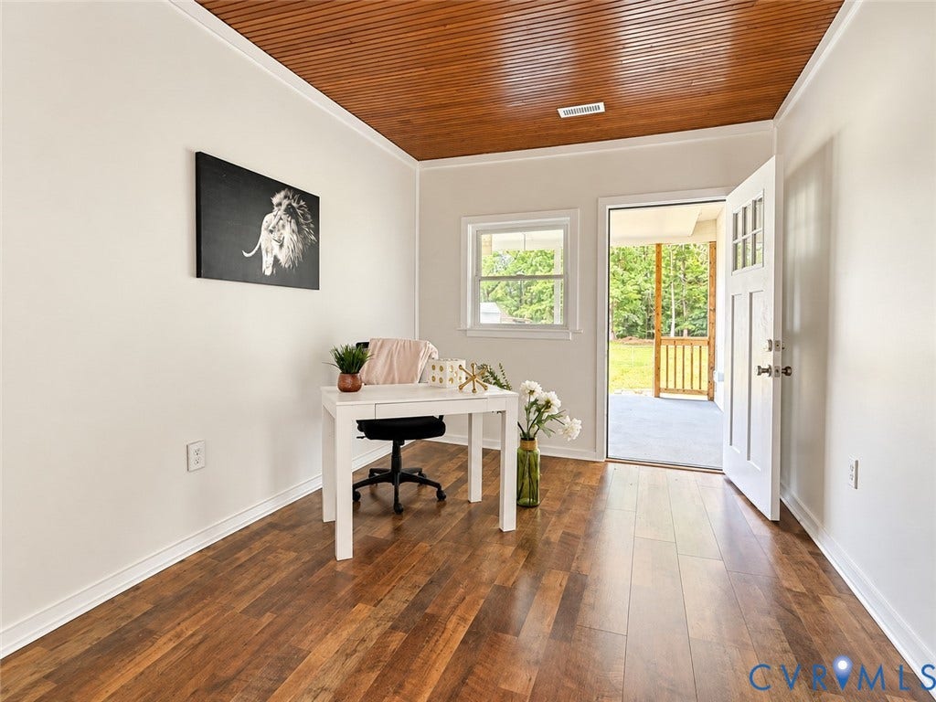 Wood-finish flooring, white trim, a wood-paneled ceiling, and a full-light door accessing a covered outdoor area