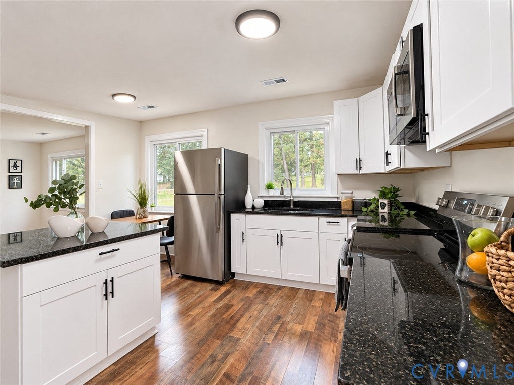 Kitchen featuring wood-finish flooring, white cabinetry, dark speckled countertops, stainless steel appliances, and ceiling-mounted lighting