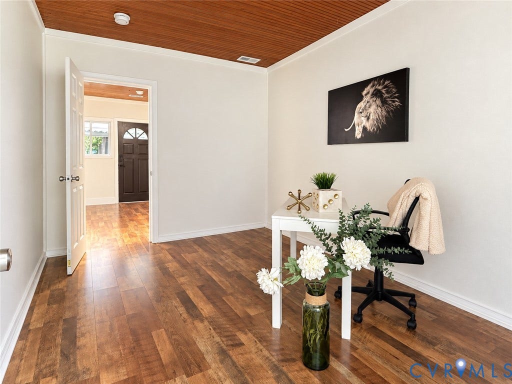 Wood-finish flooring throughout, white painted walls, and a wood-paneled ceiling