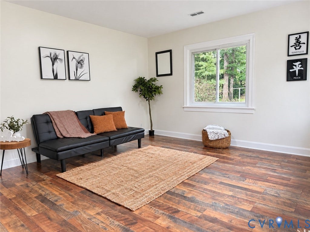 Wood-finish flooring, white trim, and a window with a white frame
