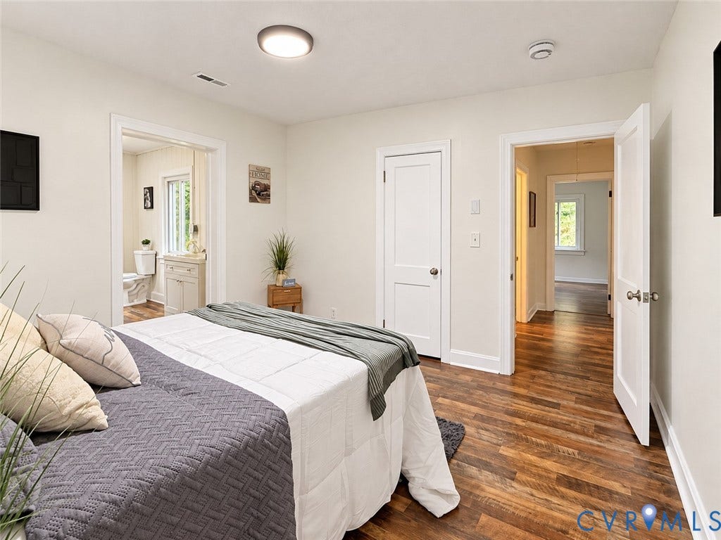 Wood-finish flooring throughout, white trim, and a flush-mount ceiling light fixture