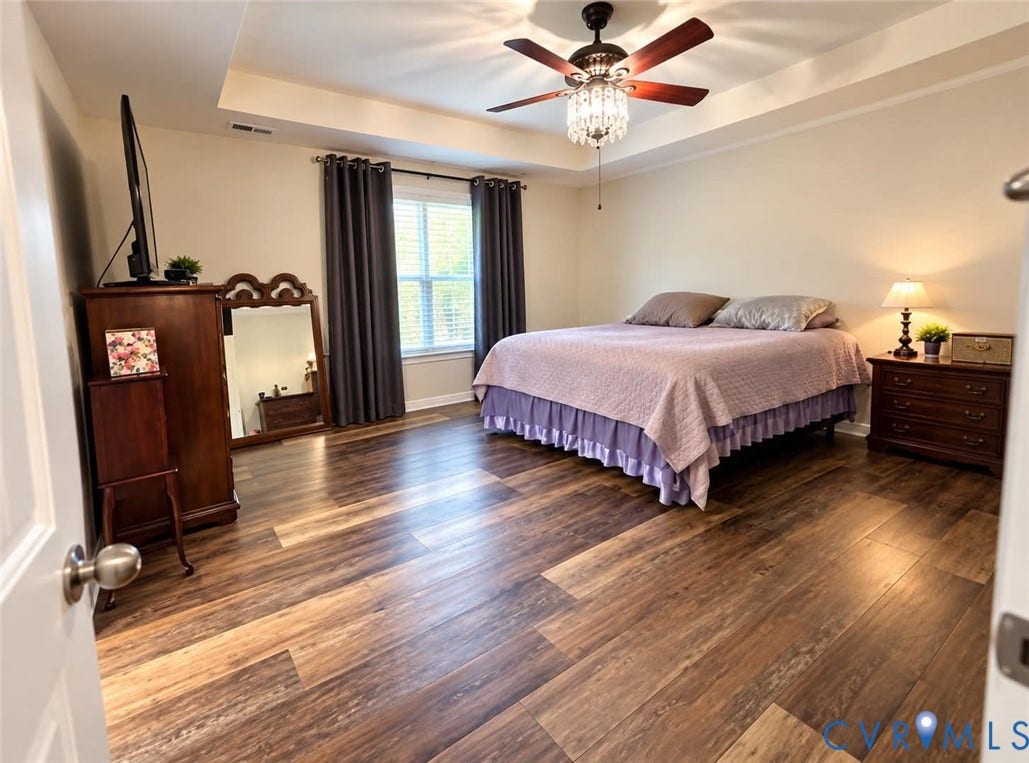 6722 Gibe Lane, Chesterfield, VA 23234 Tray ceiling, wood-finish flooring, and a central ceiling fan with an integrated crystal light fixture. This image has been digitally enhanced using AI for lighting and clarity.