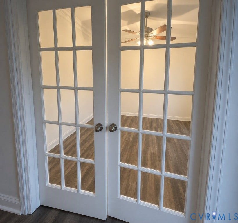 6722 Gibe Lane, Chesterfield, VA 23234 Double French doors featuring 15-pane glass insets, brushed nickel hardware, and crown molding, opening into a room with wood-finish flooring and a central ceiling fan. This image has been digitally enhanced using AI for lighting and clarity.