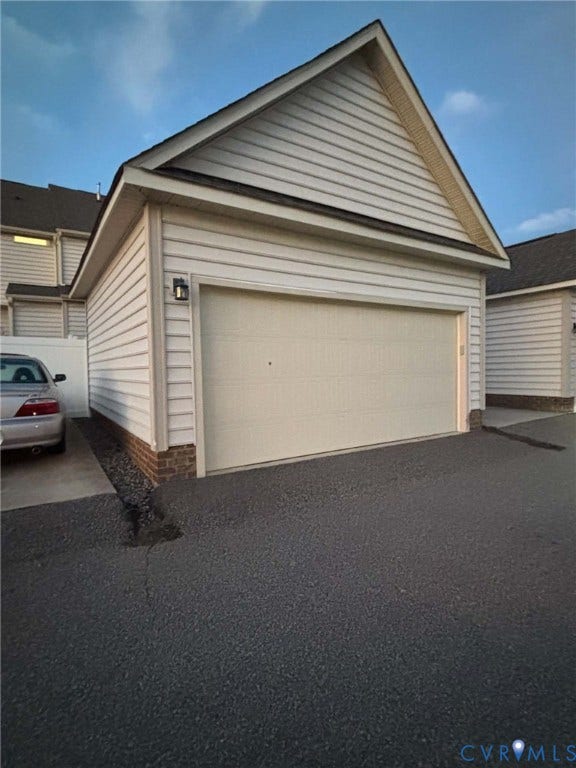 6722 Gibe Lane, Chesterfield, VA 23234 Detached garage featuring horizontal vinyl siding, a brick foundation trim, a gabled roofline, and an exterior wall-mounted light fixture