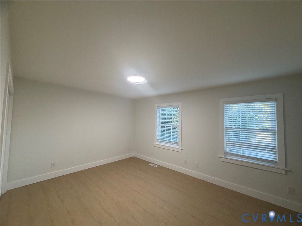 Bright interior with light wood-finish flooring, white walls, and a ceiling-mounted light fixture