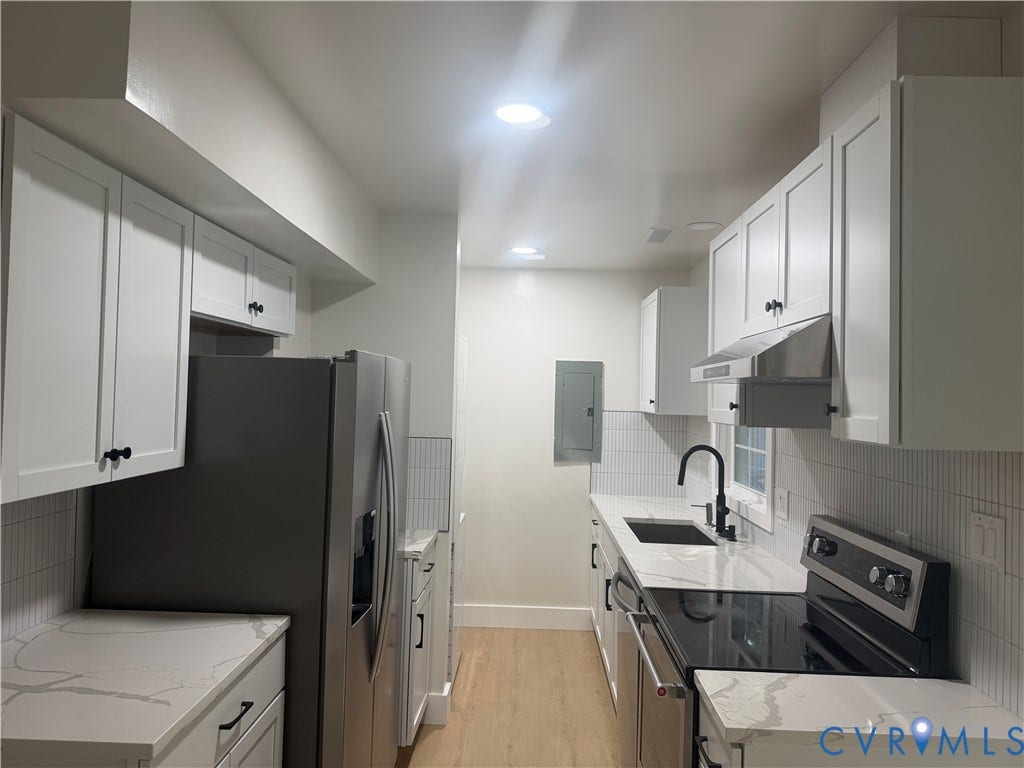 Sleek kitchen featuring white shaker cabinetry, light-toned wood-finish flooring, and white countertops