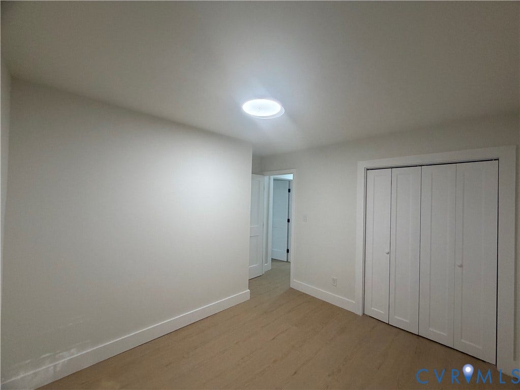 Recessed ceiling light fixture, wood-finish flooring, white walls, and bi-fold closet doors