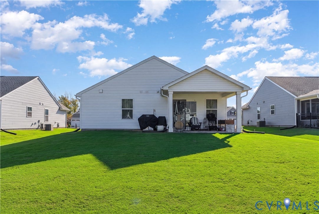 7580 Southamptonshire Way, Autumn Pines, New Kent, VA 23124 Expansive green lawn with a covered patio, featuring vinyl siding and a gabled roofline