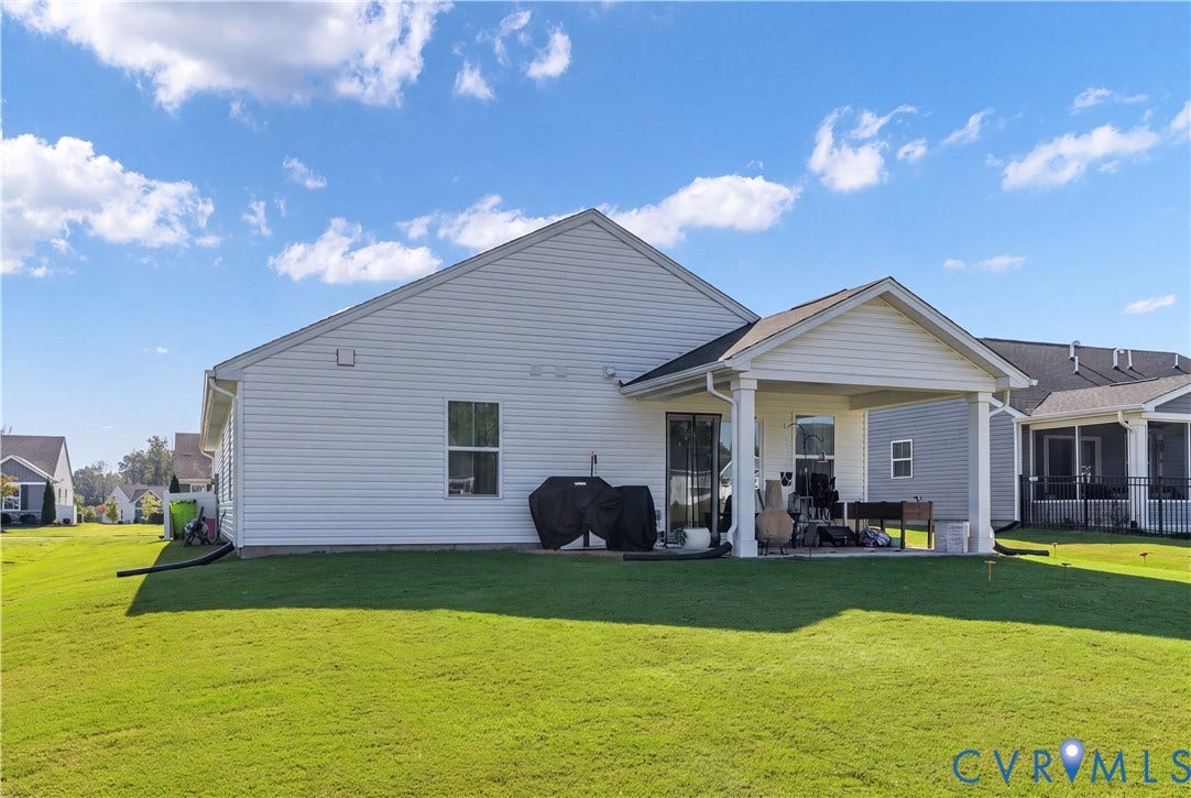 7580 Southamptonshire Way, Autumn Pines, New Kent, VA 23124 Expansive green lawn, white vinyl siding exterior, window, and covered patio with a gable roof