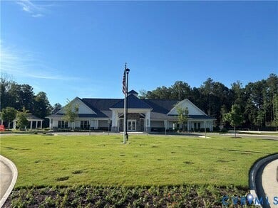 7580 Southamptonshire Way, Autumn Pines, New Kent, VA 23124 Expansive green lawn surrounds a building with a multi-gabled roofline, stone facade elements, and a covered entry