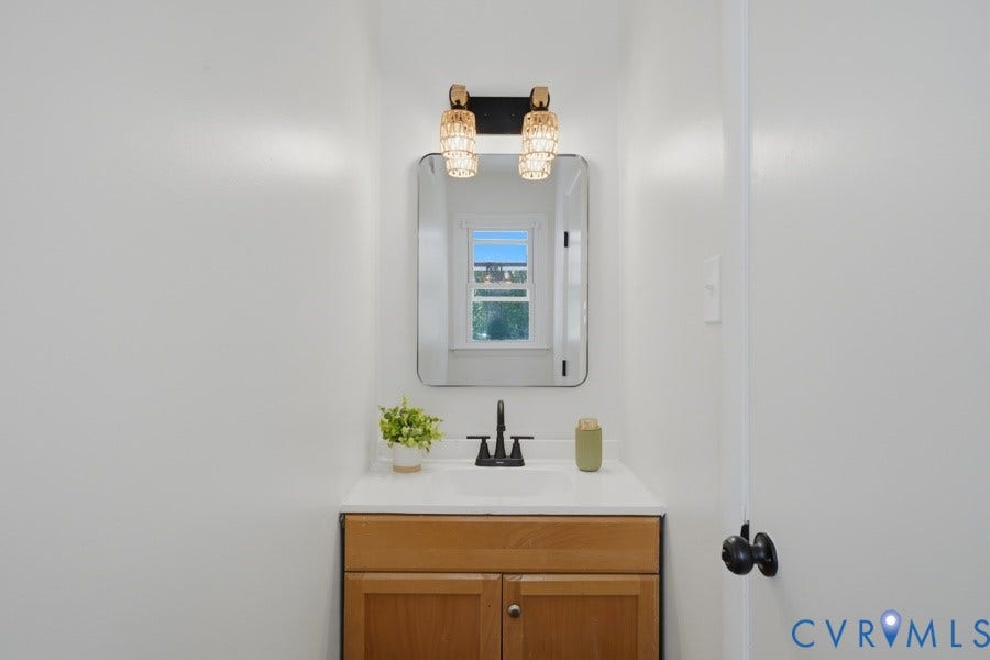 20306 Sheffield Place, Laurel Branch Farms, South Chesterfield, VA 23803 Wall-mounted vanity light with two fixtures, rectangular mirror, single-basin sink with matte black faucet, and wood-finish vanity with cabinet storage