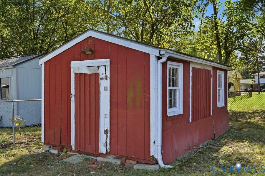 20306 Sheffield Place, Laurel Branch Farms, South Chesterfield, VA 23803 Red wood-paneled shed featuring a white trim, two single-hung windows, and a singular door