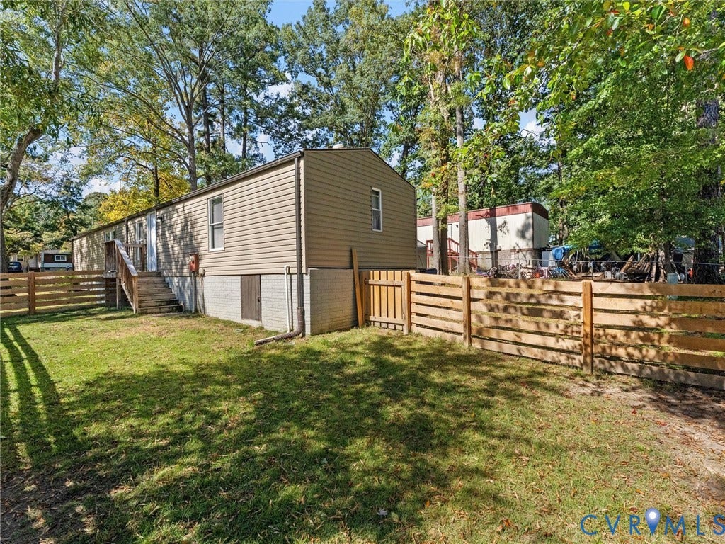 17009 Lansmill Drive, South Chesterfield, VA 23834 Expansive green yard with natural wood fencing, mature trees, and a ground-level access door