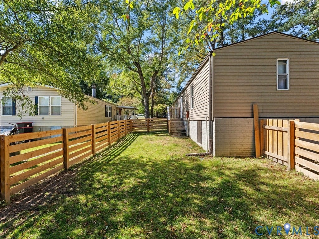 17009 Lansmill Drive, South Chesterfield, VA 23834 Expansive outdoor space featuring a wood-slat fence, mature trees, and a grassy lawn